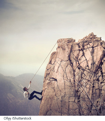 Businessman climbing large rock